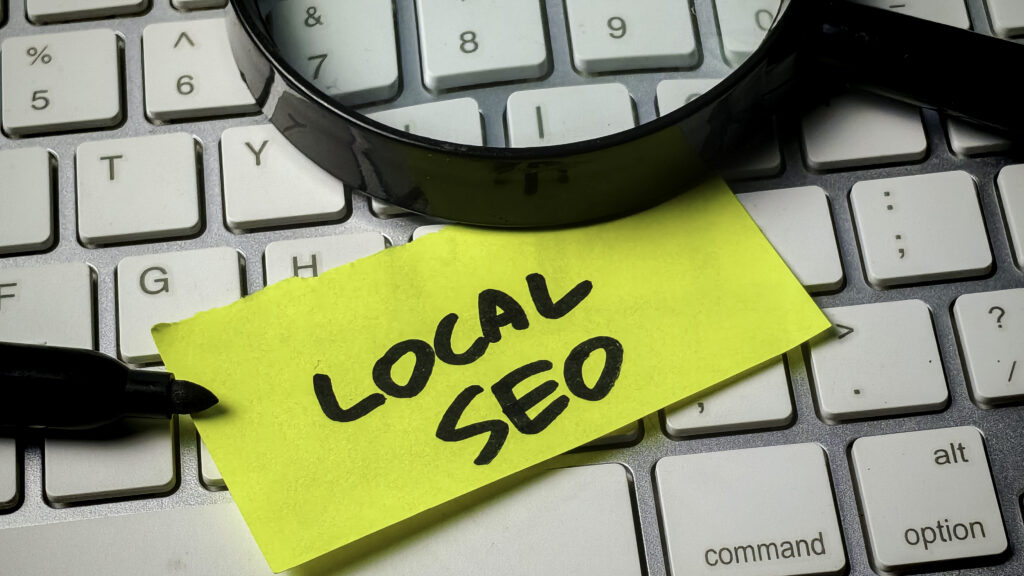 Magnifying glass over a "Local SEO" sticky note on a keyboard, representing local search optimization for small businesses in Sumter, SC