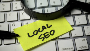 Magnifying glass over a "Local SEO" sticky note on a keyboard, representing local search optimization for small businesses in Sumter, SC